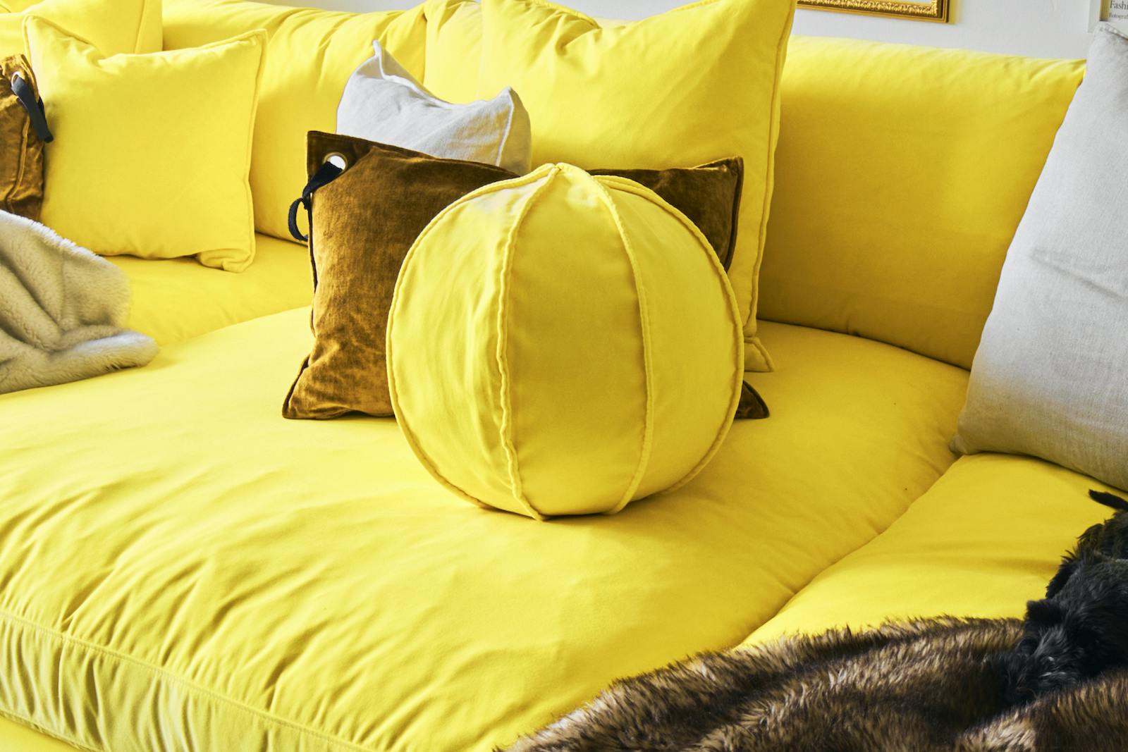 30x30cm bred bollkudde med en dekorativ söm i gul polyestersammet.