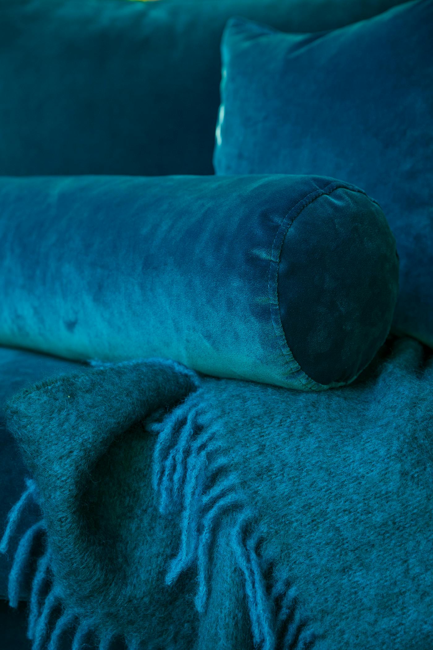 Cylinderkudde, 19x60cm, i blå polyestersammet. Blå mohairpläd, 150x140cm.