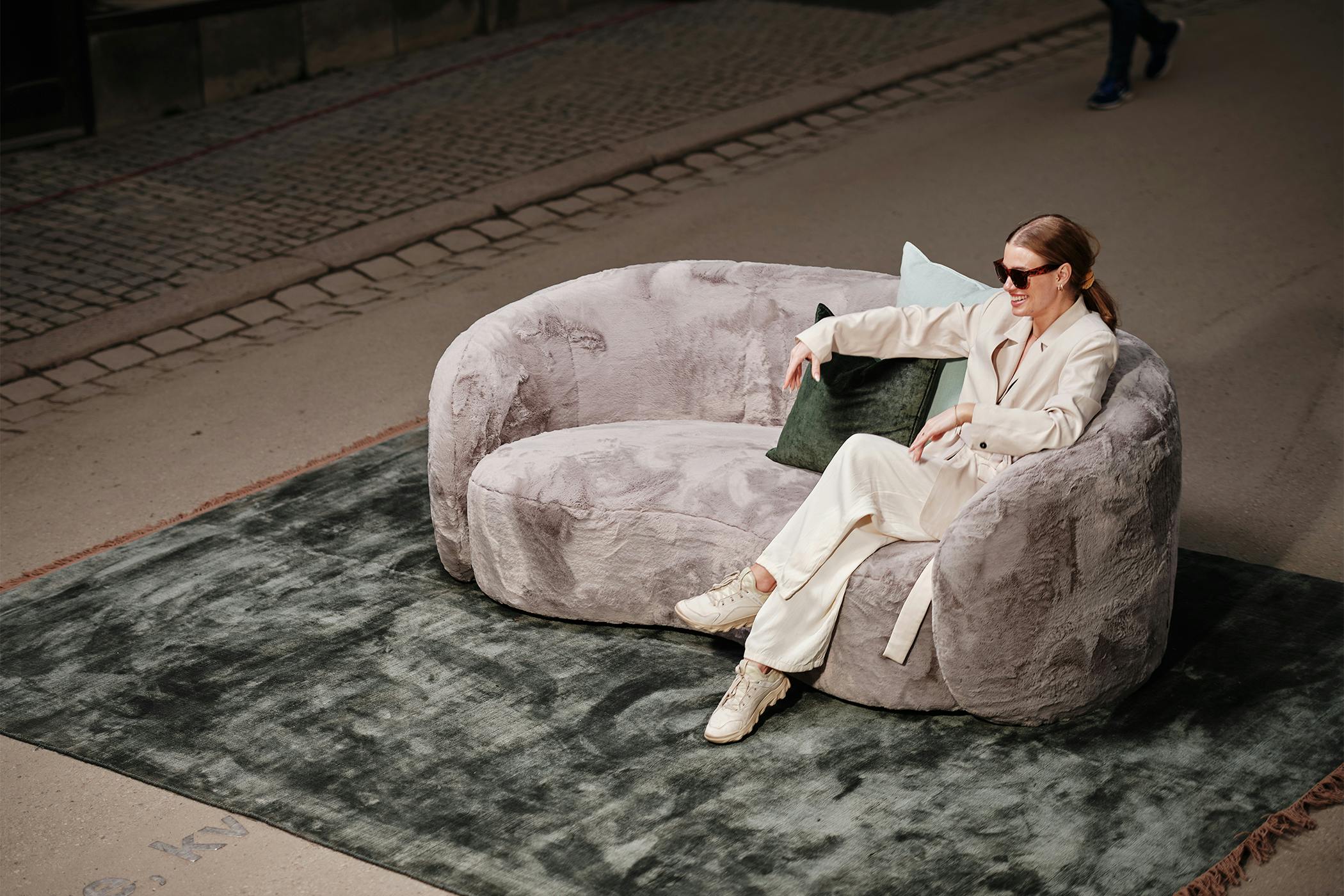 200cm bred soffa i kallskum med rundad sits och rygg, klädd i grå flufftyg i 100% polyester. Grön viskosmatta, 170x240cm. 